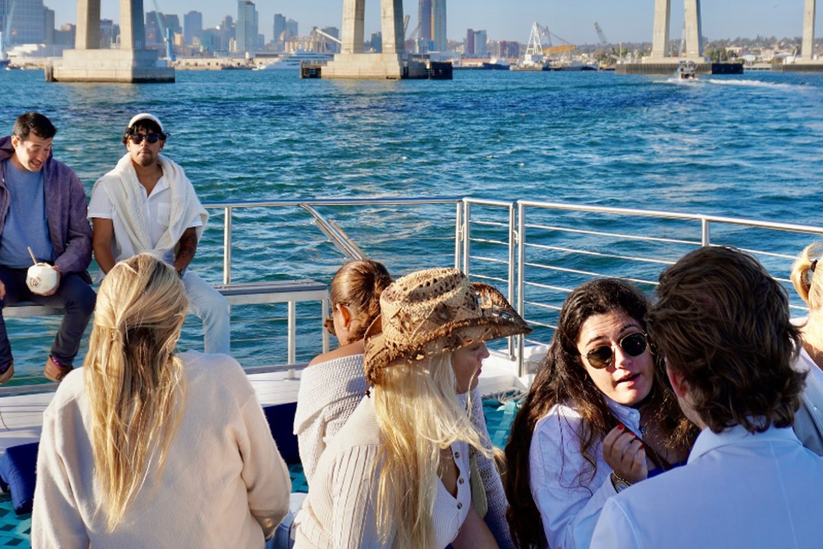 A group with coconut drinks on Athena's foredeck as she approaches the Coronado Bridge