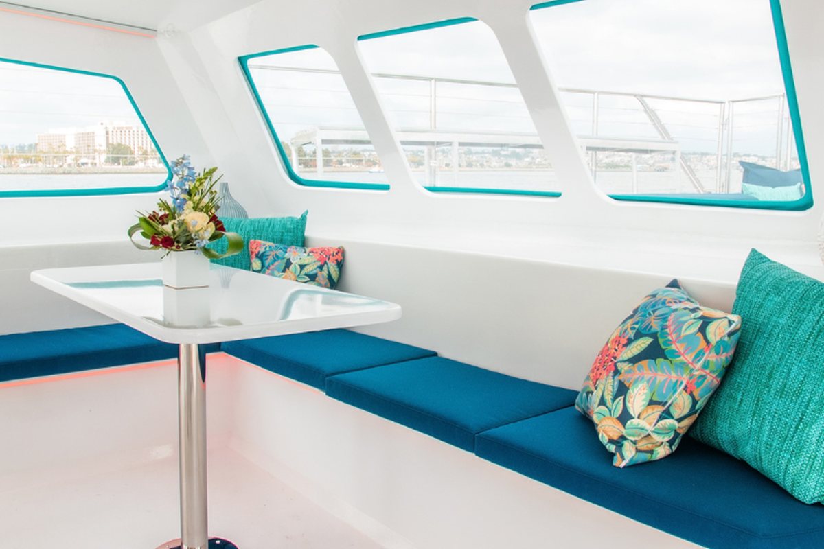 Athena's bright cabin salon with teal bench seating and wraparound windows
