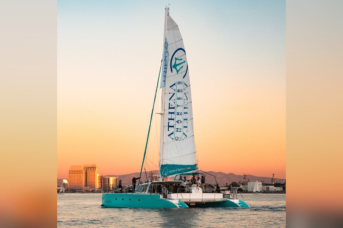 Athena under sail on San Diego Bay at sunset, the downtown skyline behind her