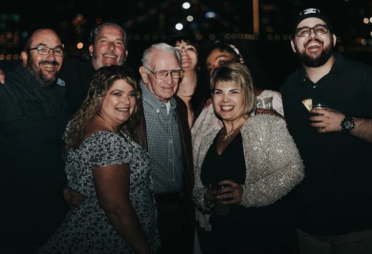 A family group celebrating together on Triton's deck with the city lights behind them