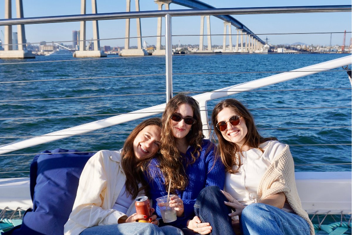 Three friends with drinks on Triton's bow beneath the Coronado Bridge