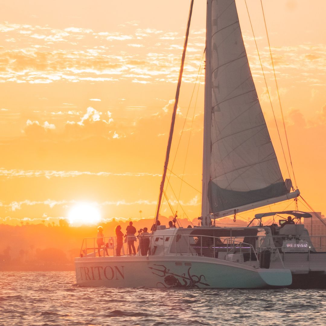 Guests on deck as the sun sets behind the Triton's sail