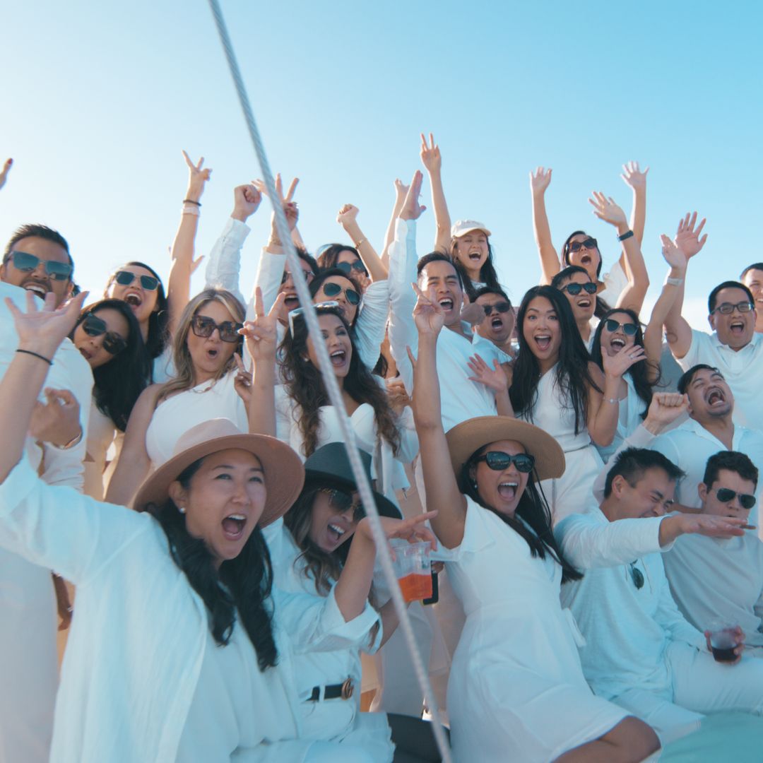 Guests in white with their arms up on Triton's deck