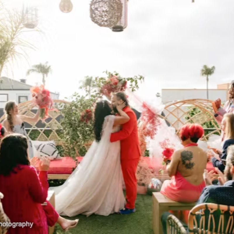 Outdoor garden ceremony at Nolita House, guests in red gathered around the couple