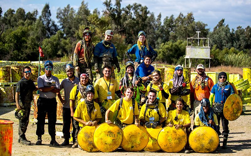 Paintball players in yellow jerseys posed together at a San Diego field