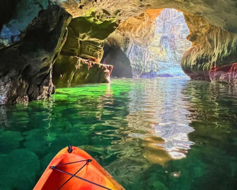 Kayak gliding through a green-lit sea cave at La Jolla Cove