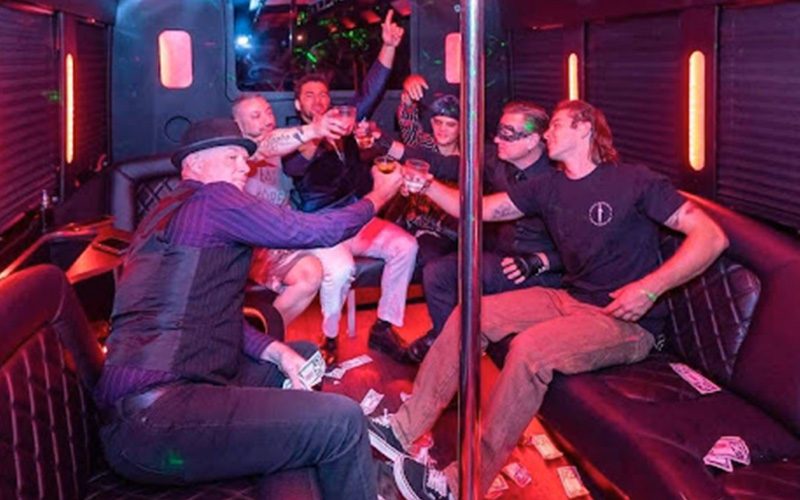 Inside a party bus lit with red neon, guests sitting along the bench seats