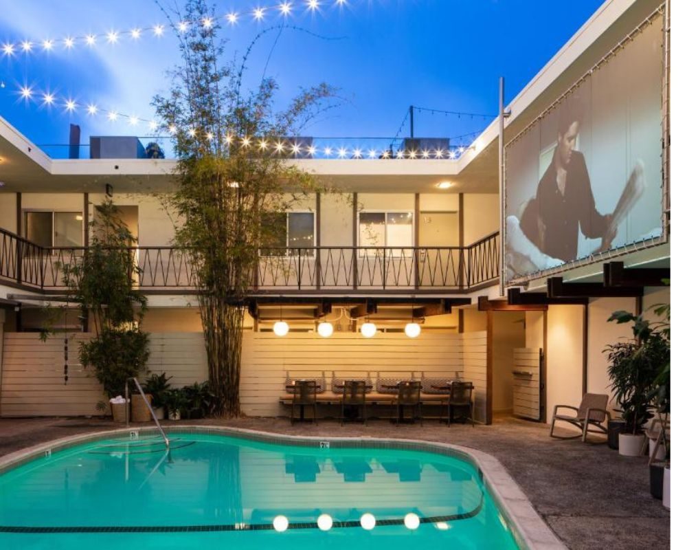 Hotel pool at dusk with a film projected onto the wall above the water