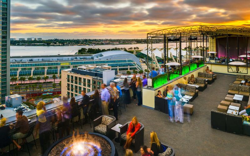 Rooftop bar tables looking out over downtown San Diego at sunset